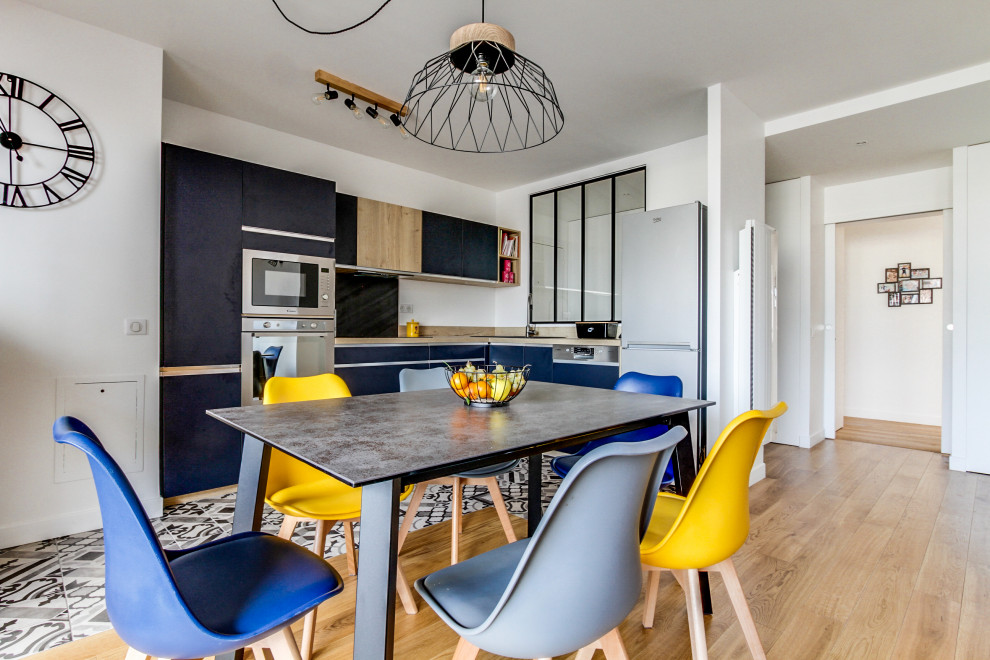 Medium sized contemporary l-shaped open plan kitchen in Paris with blue cabinets, laminate countertops, beige splashback, stainless steel appliances, ceramic flooring, no island, beige worktops, flat-panel cabinets and multi-coloured floors.