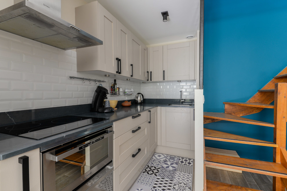 パリにある小さなモダンスタイルのおしゃれなキッチン (一体型シンク、ベージュのキャビネット、珪岩カウンター、白いキッチンパネル、サブウェイタイルのキッチンパネル、シルバーの調理設備、セラミックタイルの床、アイランドなし、ベージュの床、黒いキッチンカウンター) の写真