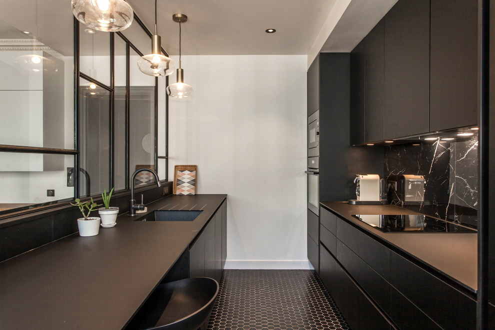 Exemple d'une cuisine ouverte linéaire tendance de taille moyenne avec un évier encastré, des portes de placard noires, un sol en carrelage de porcelaine, îlot, un sol noir et plan de travail noir.