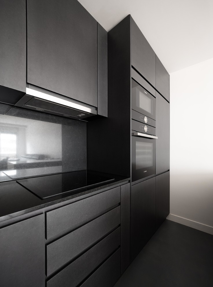 Modern inredning av ett mellanstort grå grått kök, med en undermonterad diskho, luckor med profilerade fronter, grå skåp, granitbänkskiva, grått stänkskydd, svarta vitvaror, betonggolv, en köksö och grått golv