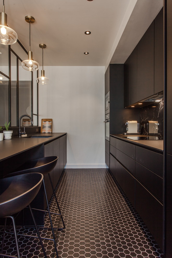 Cette image montre une cuisine ouverte linéaire design de taille moyenne avec un évier encastré, des portes de placard noires, un sol en carrelage de porcelaine, îlot, un sol noir et plan de travail noir.
