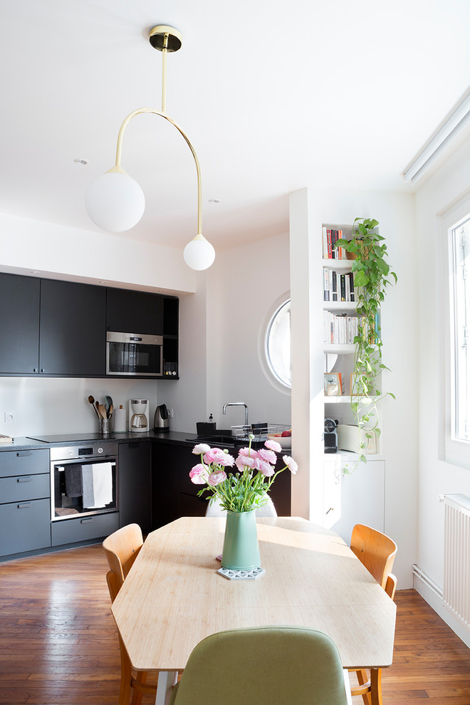 Eat-in kitchen - mid-sized contemporary l-shaped medium tone wood floor eat-in kitchen idea in Paris with an undermount sink, black cabinets, laminate countertops and black countertops