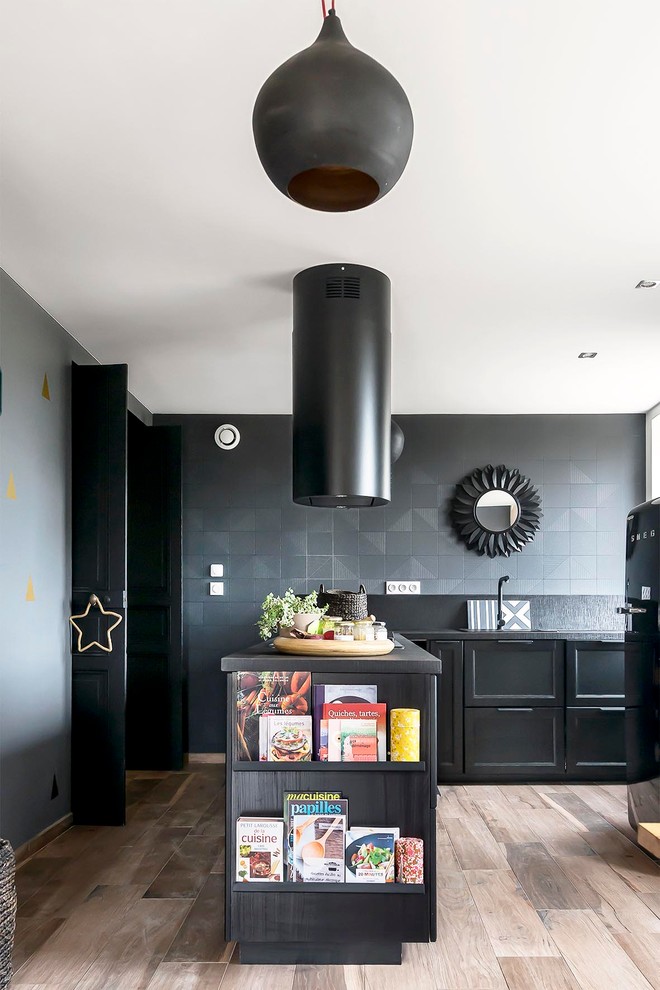 На фото: отдельная, угловая кухня среднего размера в современном стиле с черными фасадами, черным фартуком, черной техникой, светлым паркетным полом, полуостровом и барной стойкой