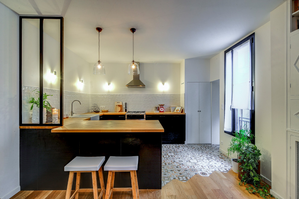 Design ideas for a medium sized contemporary u-shaped open plan kitchen in Paris with a submerged sink, black cabinets, wood worktops, white splashback, ceramic splashback, cement flooring, an island and beige floors.