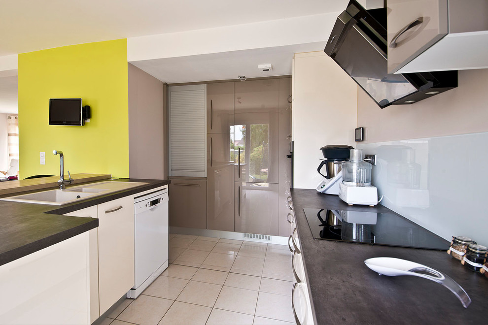This is an example of a medium sized modern single-wall kitchen/diner in Nantes with a single-bowl sink, flat-panel cabinets, white cabinets, laminate countertops, white splashback, glass tiled splashback, integrated appliances, ceramic flooring, an island and beige floors.