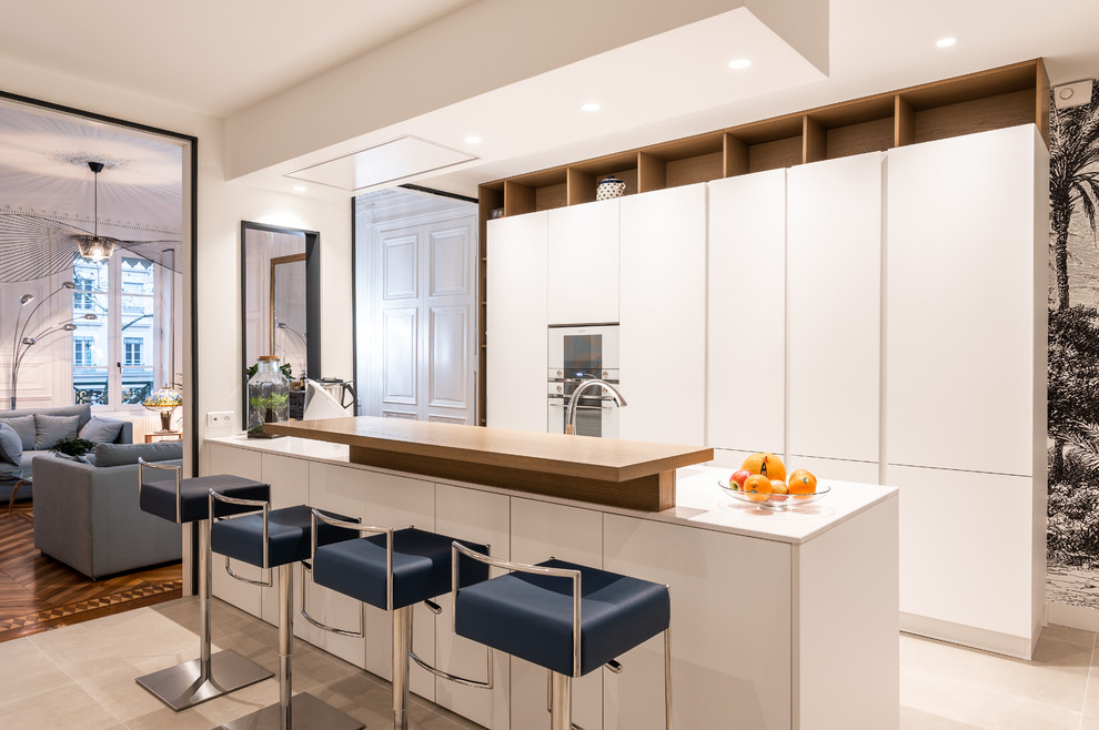 Imagen de cocina contemporánea con armarios con paneles lisos, puertas de armario blancas, electrodomésticos blancos, una isla, suelo beige y encimeras blancas