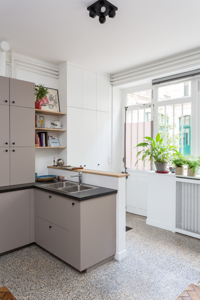 Photo of a medium sized urban l-shaped open plan kitchen in Other with a built-in sink, flat-panel cabinets, brown cabinets, granite worktops, beige splashback, ceramic splashback, stainless steel appliances, terrazzo flooring, no island, multi-coloured floors and black worktops.