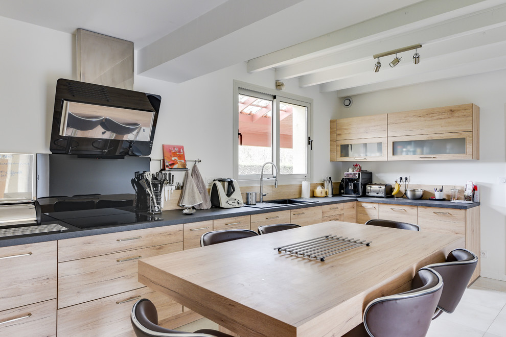 Exempel på ett avskilt, stort modernt grå grått l-kök, med en enkel diskho, luckor med glaspanel, skåp i ljust trä, laminatbänkskiva, stänkskydd i trä, svarta vitvaror, klinkergolv i keramik och vitt golv