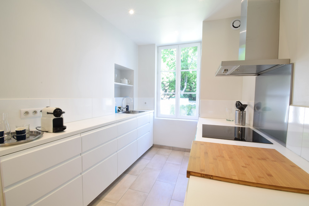 This is an example of a medium sized scandinavian galley open plan kitchen in Paris with ceramic flooring, an island, brown floors, a single-bowl sink, flat-panel cabinets, white cabinets, wood worktops, white splashback, metro tiled splashback, stainless steel appliances and white worktops.