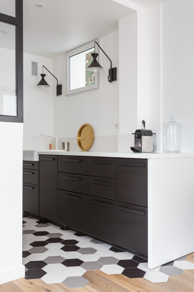Bild på ett litet funkis vit vitt kök, med en rustik diskho, släta luckor, flerfärgat golv, svarta skåp, bänkskiva i kvartsit, vitt stänkskydd, stänkskydd i sten, svarta vitvaror och klinkergolv i keramik