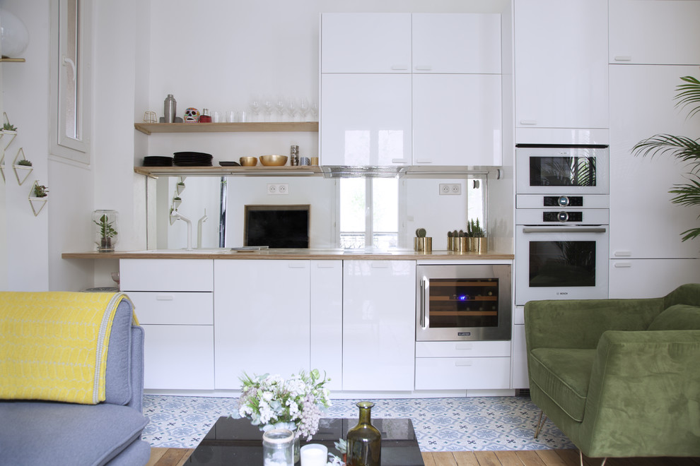 Idéer för att renovera ett mellanstort funkis brun linjärt brunt kök och matrum, med en undermonterad diskho, luckor med profilerade fronter, vita skåp, träbänkskiva, spegel som stänkskydd, vita vitvaror, cementgolv och blått golv