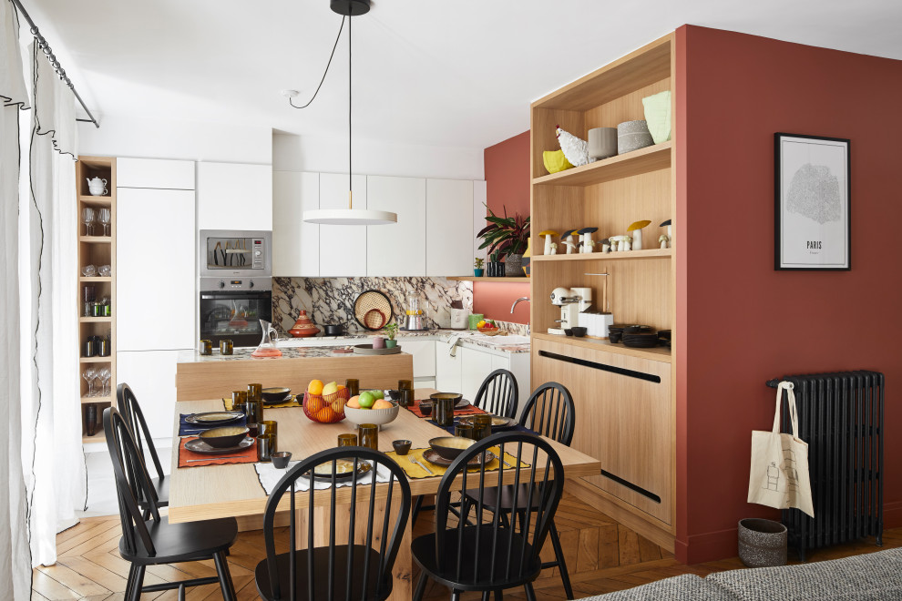 Eat-in kitchen - mid-sized contemporary l-shaped brown floor eat-in kitchen idea in Paris with a drop-in sink, flat-panel cabinets, white cabinets, gray backsplash, paneled appliances, an island and gray countertops