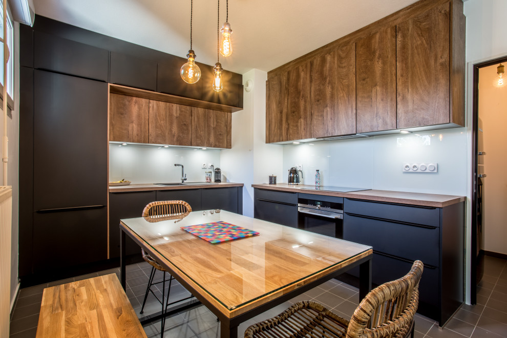 Idéer för att renovera ett avskilt funkis brun brunt l-kök, med en nedsänkt diskho, släta luckor, svarta skåp, träbänkskiva, glaspanel som stänkskydd, integrerade vitvaror och brunt golv