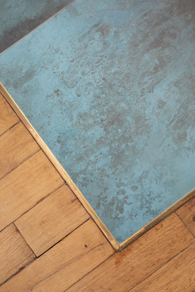 Cette image montre une petite cuisine ouverte parallèle méditerranéenne en bois clair avec un évier encastré, un placard à porte plane, une crédence bleue, une crédence en céramique, un électroménager noir, un sol en carrelage de céramique, un sol bleu, plan de travail noir, un plan de travail en surface solide et une péninsule.