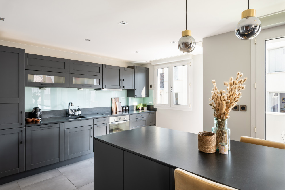 Design ideas for a medium sized scandi single-wall open plan kitchen in Saint-Etienne with granite worktops, black splashback, granite splashback, an island, grey floors and black worktops.