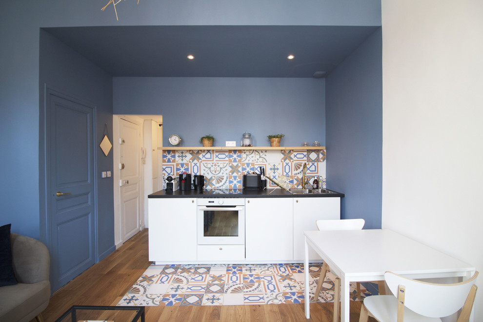 Источник вдохновения для домашнего уюта: кухня с белыми фасадами, разноцветным фартуком, фартуком из керамической плитки и черной столешницей