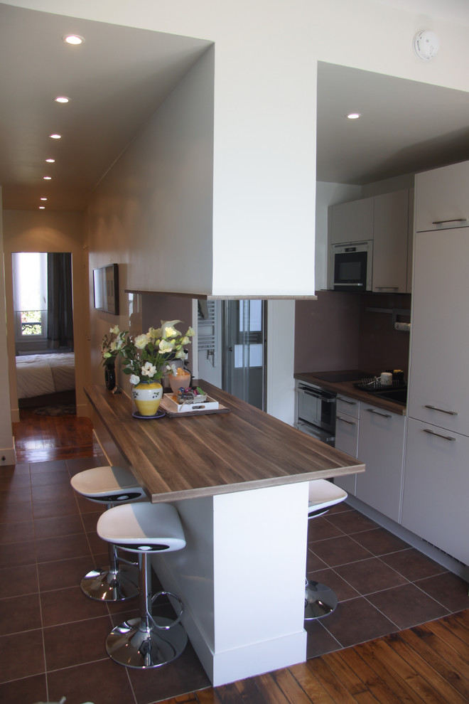 Cette photo montre une petite cuisine ouverte parallèle moderne avec un sol en bois brun.