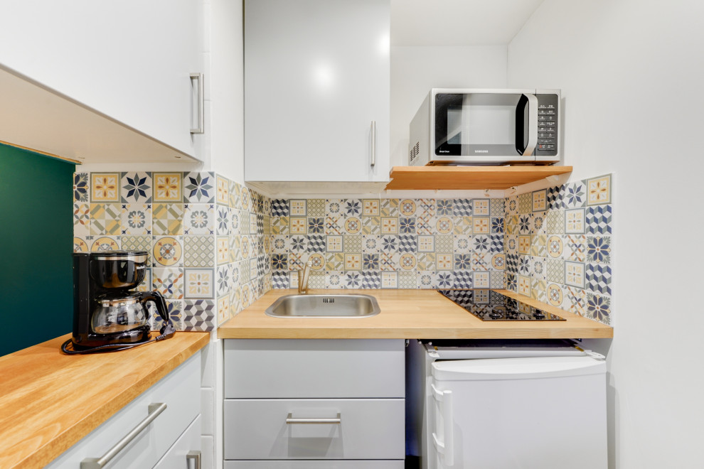 Exempel på ett litet eklektiskt beige beige kök, med en undermonterad diskho, luckor med profilerade fronter, grå skåp, träbänkskiva, flerfärgad stänkskydd, stänkskydd i cementkakel, vita vitvaror, linoleumgolv och grått golv