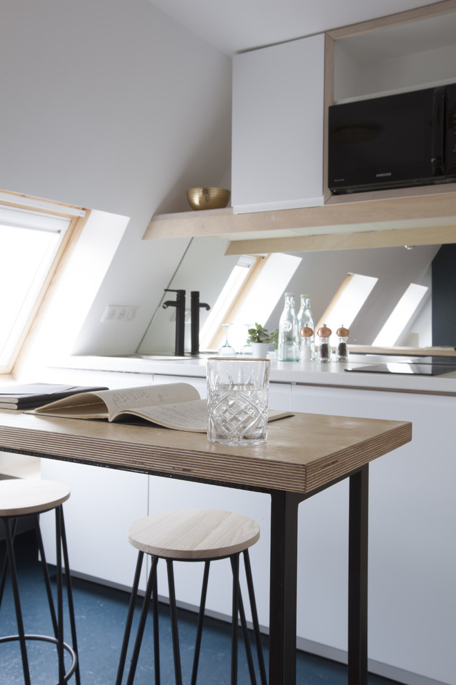 Inspiration for a small contemporary galley open plan kitchen in Paris with a single-bowl sink, flat-panel cabinets, light wood cabinets, wood worktops, black splashback, glass sheet splashback, black appliances, concrete flooring, a breakfast bar and blue floors.