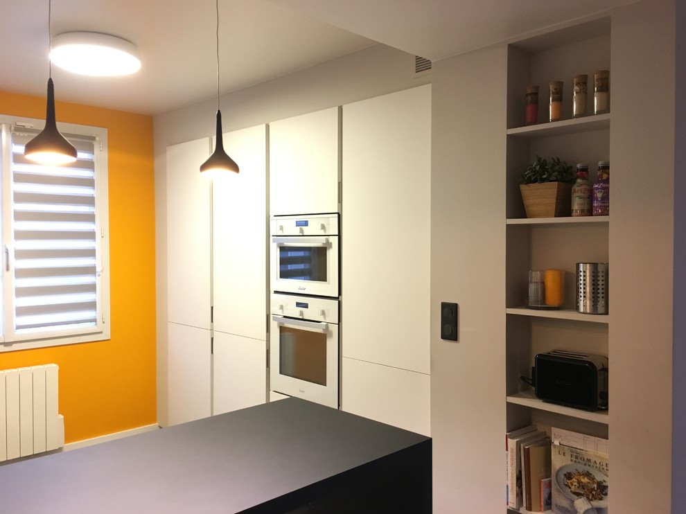 Источник вдохновения для домашнего уюта: параллельная кухня среднего размера в современном стиле с обеденным столом, одинарной мойкой, белыми фасадами, зеркальным фартуком, белой техникой и серым полом