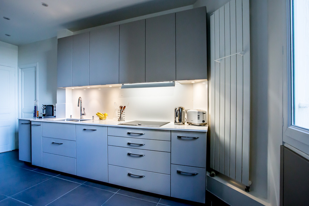 Photo of a medium sized contemporary galley enclosed kitchen in Paris with an integrated sink, beaded cabinets, white cabinets, quartz worktops, white splashback, stainless steel appliances, ceramic flooring, no island and grey floors.