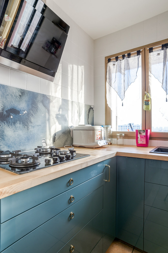 Modern inredning av ett litet brun brunt kök, med en integrerad diskho, blå skåp, träbänkskiva, flerfärgad stänkskydd, rostfria vitvaror, klinkergolv i keramik, luckor med profilerade fronter, stänkskydd i stickkakel och brunt golv