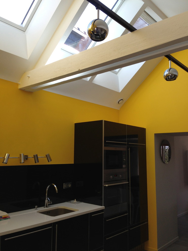 Immagine di una cucina lineare design chiusa e di medie dimensioni con lavello sottopiano, ante lisce, ante nere, paraspruzzi nero, elettrodomestici da incasso e pavimento con piastrelle in ceramica