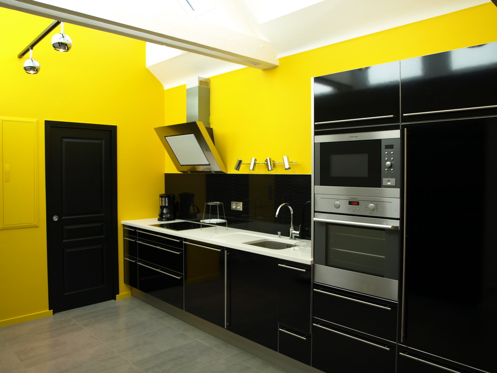 レンヌにある高級な広いコンテンポラリースタイルのおしゃれなキッチン (黒いキャビネット、アンダーカウンターシンク、黒いキッチンパネル、パネルと同色の調理設備、セラミックタイルの床、グレーの床) の写真