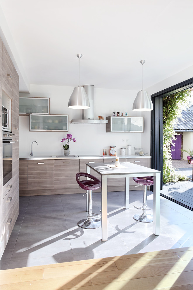 Inspiration for a large contemporary l-shaped kitchen/diner in Rennes with flat-panel cabinets, medium wood cabinets, laminate countertops, concrete flooring, an island and stainless steel appliances.