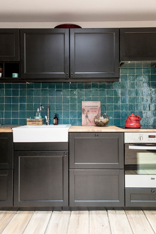 Foto på ett mellanstort funkis linjärt kök med öppen planlösning, med en rustik diskho, svarta skåp, träbänkskiva, blått stänkskydd, stänkskydd i terrakottakakel, ljust trägolv och rostfria vitvaror