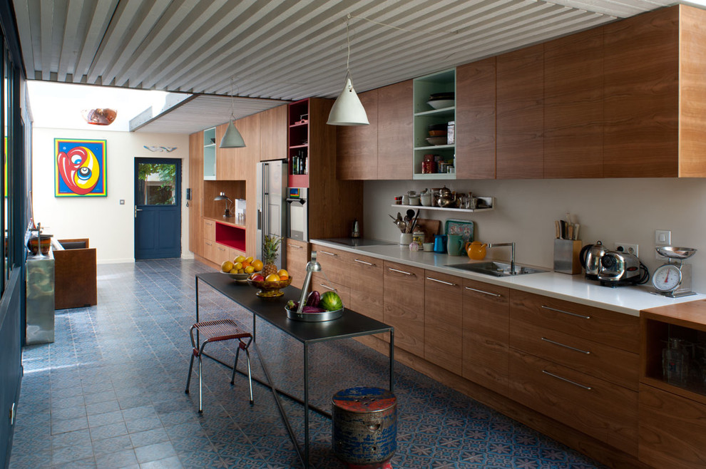 Photo of an urban single-wall open plan kitchen in Paris with a submerged sink, beaded cabinets, brown cabinets, composite countertops, white splashback, matchstick tiled splashback, stainless steel appliances, cement flooring, an island and multi-coloured floors.