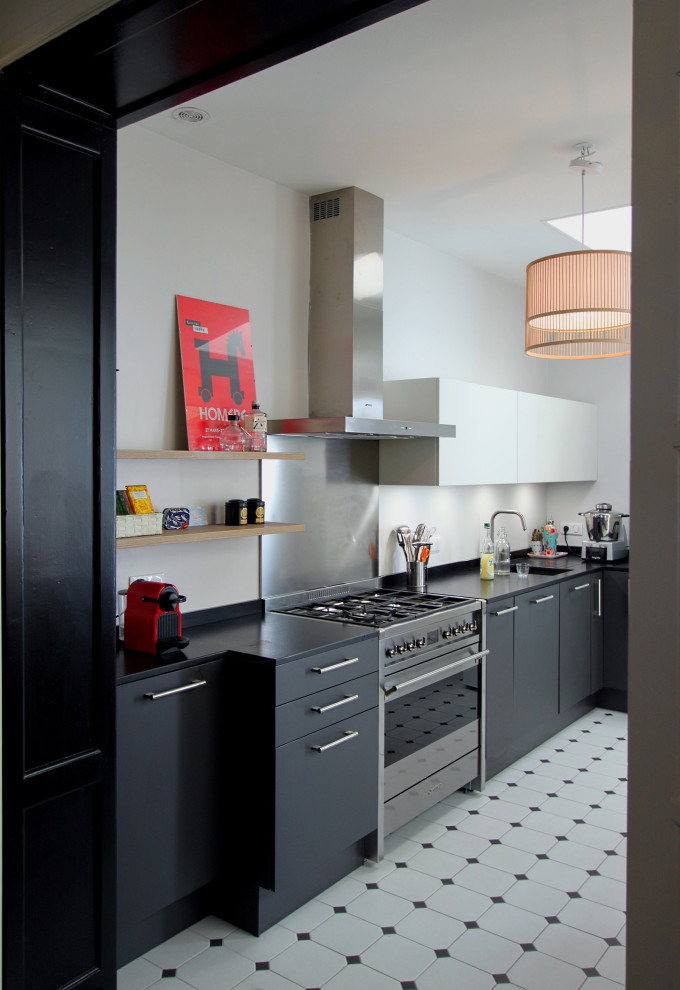 Bild på ett mellanstort funkis svart svart kök, med en undermonterad diskho, svarta skåp, granitbänkskiva, stänkskydd med metallisk yta, rostfria vitvaror, klinkergolv i keramik, vitt golv och släta luckor