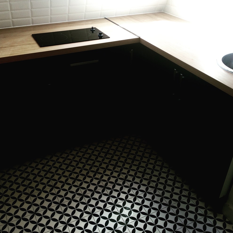Photo of a small modern l-shaped enclosed kitchen in Paris with a submerged sink, flat-panel cabinets, black cabinets, wood worktops, white splashback, metro tiled splashback, integrated appliances, lino flooring and no island.