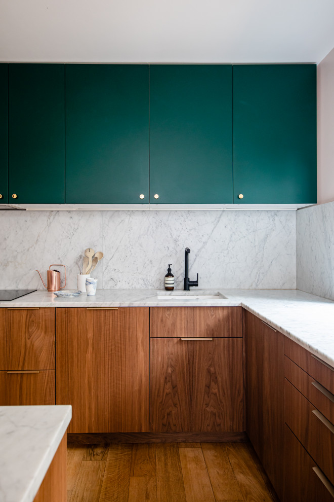 This is an example of a contemporary l-shaped kitchen in Paris with a submerged sink, flat-panel cabinets, medium wood cabinets, white splashback, stone slab splashback, medium hardwood flooring, an island, brown floors and white worktops.