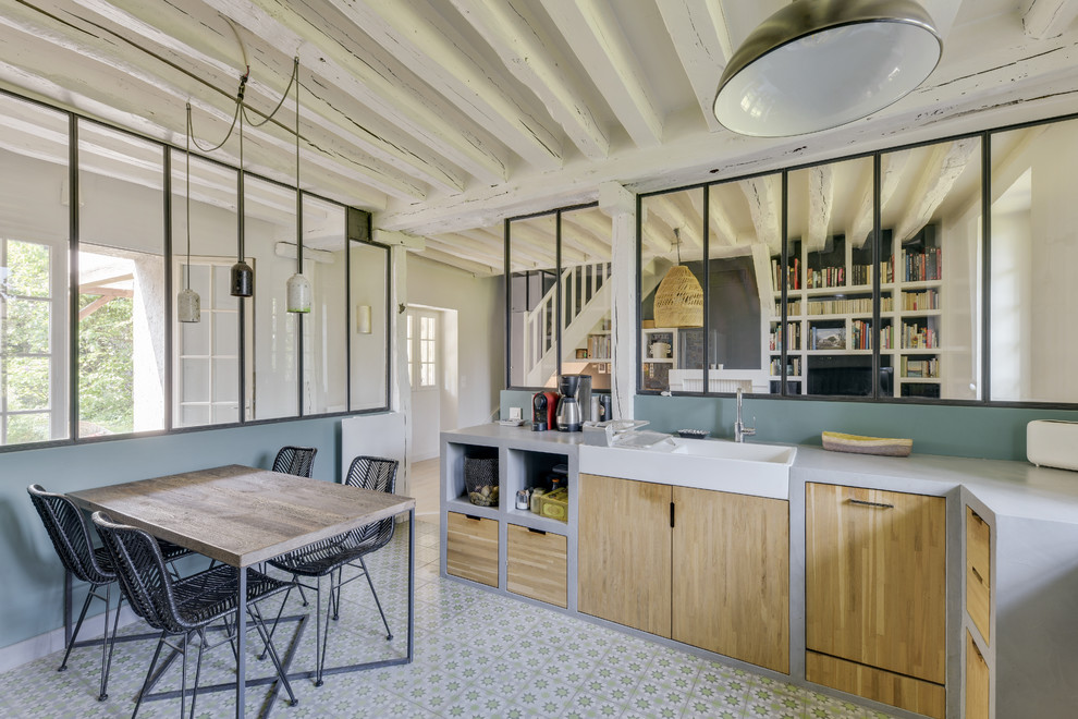 This is an example of a large urban l-shaped enclosed kitchen in Paris with a belfast sink, open cabinets, light wood cabinets, concrete worktops, green splashback, black appliances, cement flooring, no island, green floors and grey worktops.