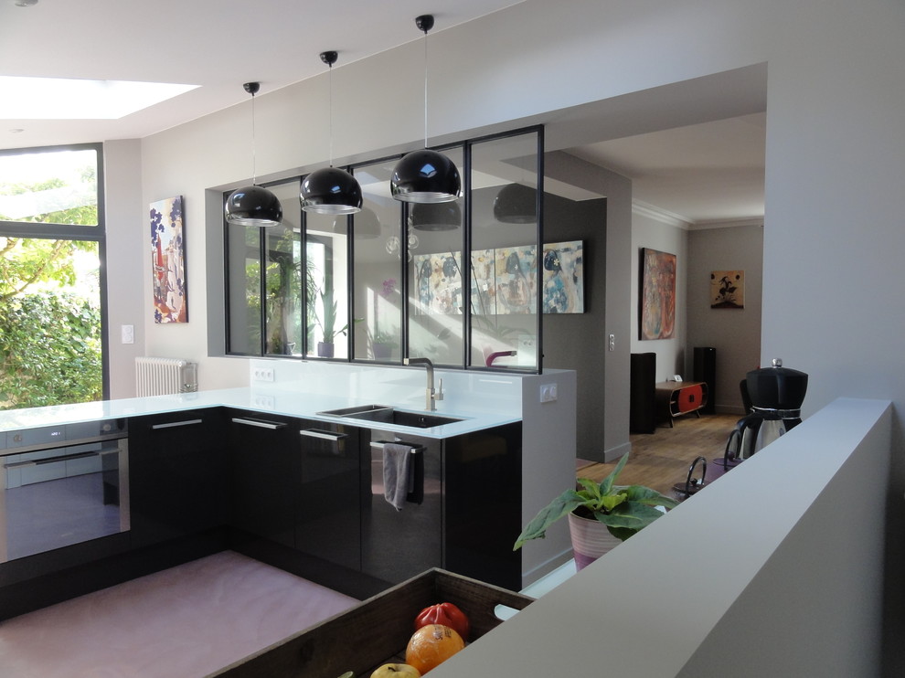 Design ideas for a large modern kitchen in Nantes with a double-bowl sink, glass worktops, white splashback, glass sheet splashback, concrete flooring and integrated appliances.