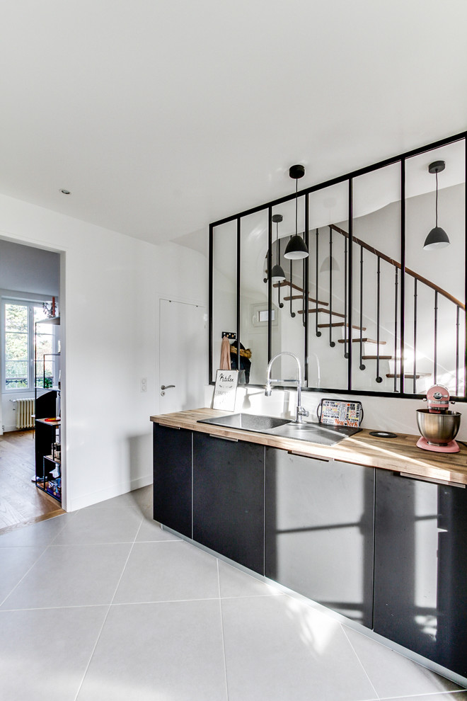 Scandi kitchen in Paris with a submerged sink, beaded cabinets, grey cabinets, laminate countertops, black appliances, ceramic flooring, a breakfast bar, grey floors and beige worktops.