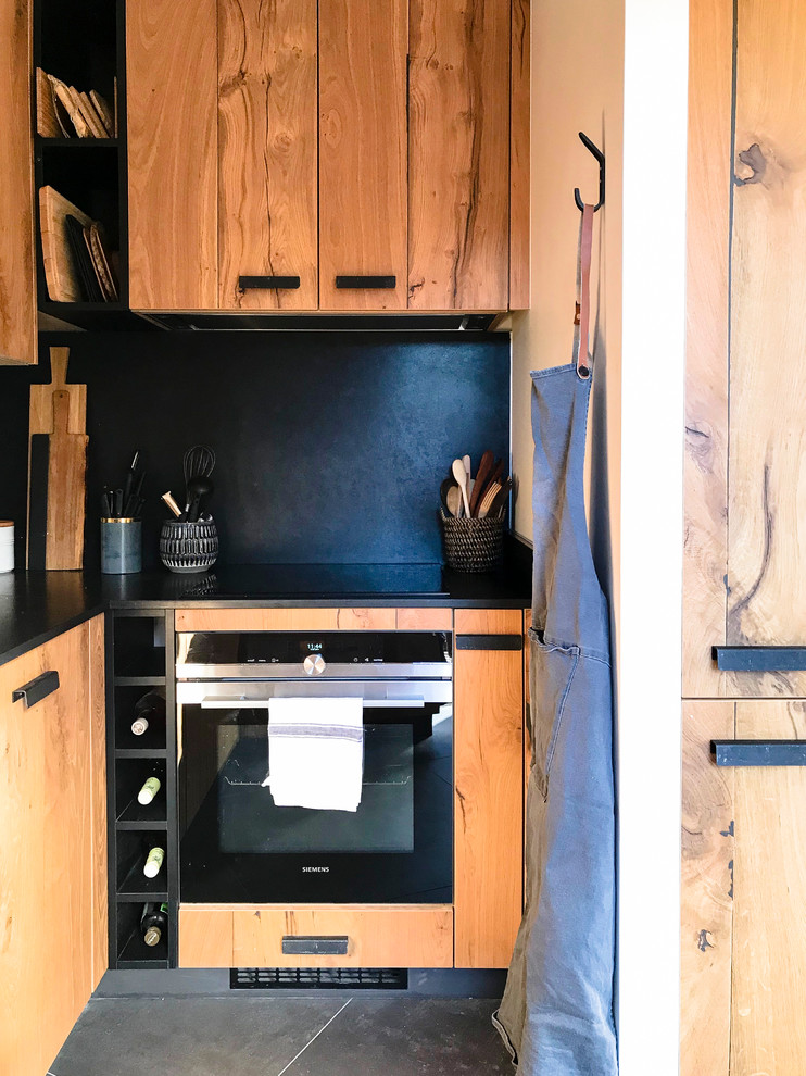 Small rustic u-shaped open plan kitchen in Lyon with a submerged sink, beaded cabinets, light wood cabinets, black splashback, black appliances, ceramic flooring, no island, grey floors and black worktops.