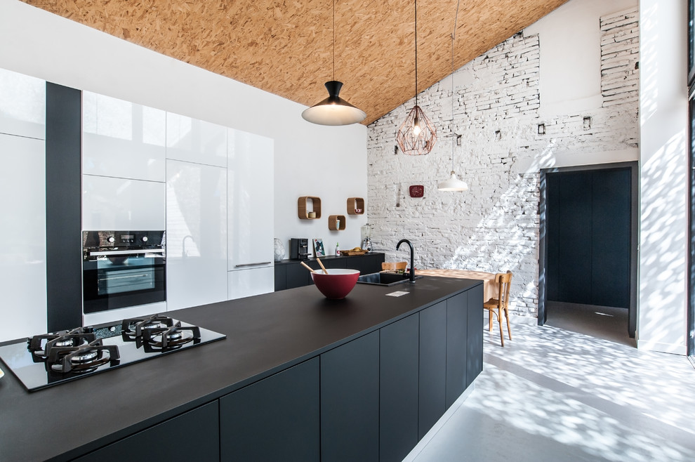 Foto på ett funkis kök och matrum, med en enkel diskho, släta luckor, svarta vitvaror och en köksö