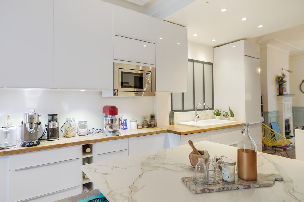 Exempel på ett mellanstort modernt vit linjärt vitt kök och matrum, med marmorbänkskiva, vitt stänkskydd, glaspanel som stänkskydd, klinkergolv i keramik, en köksö och grått golv