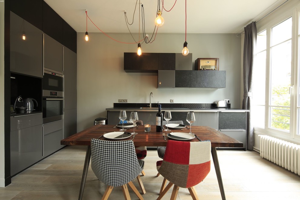 Große Moderne Wohnküche in L-Form mit flächenbündigen Schrankfronten, grauen Schränken, Küchengeräten aus Edelstahl, hellem Holzboden und Unterbauwaschbecken in Paris