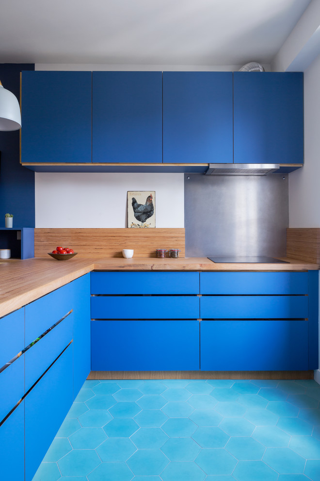 パリにあるコンテンポラリースタイルのおしゃれなキッチン (フラットパネル扉のキャビネット、青いキャビネット、木材カウンター、メタリックのキッチンパネル、ターコイズの床、ベージュのキッチンカウンター、シングルシンク、木材のキッチンパネル、ステンレスのキッチンパネル、カラー調理設備、セラミックタイルの床) の写真