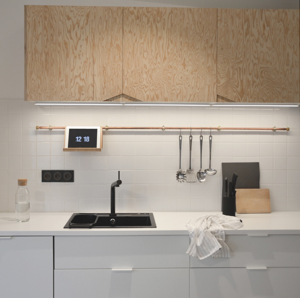 Inspiration för mellanstora nordiska linjära kök med öppen planlösning, med en undermonterad diskho, skåp i ljust trä, laminatbänkskiva, vitt stänkskydd, stänkskydd i tunnelbanekakel, svarta vitvaror och betonggolv