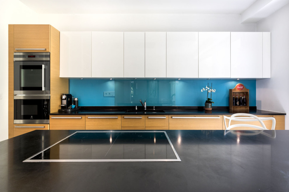 Design ideas for an expansive contemporary galley open plan kitchen in Paris with an integrated sink, beaded cabinets, light wood cabinets, granite worktops, blue splashback, glass sheet splashback, stainless steel appliances, ceramic flooring, an island, grey floors, black worktops and a drop ceiling.
