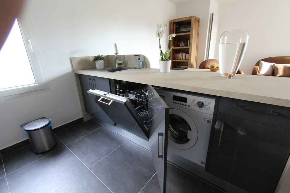 Immagine di una lavanderia contemporanea di medie dimensioni con paraspruzzi con piastrelle in pietra, ante nere, top in laminato, paraspruzzi grigio, pavimento in legno massello medio e pavimento nero