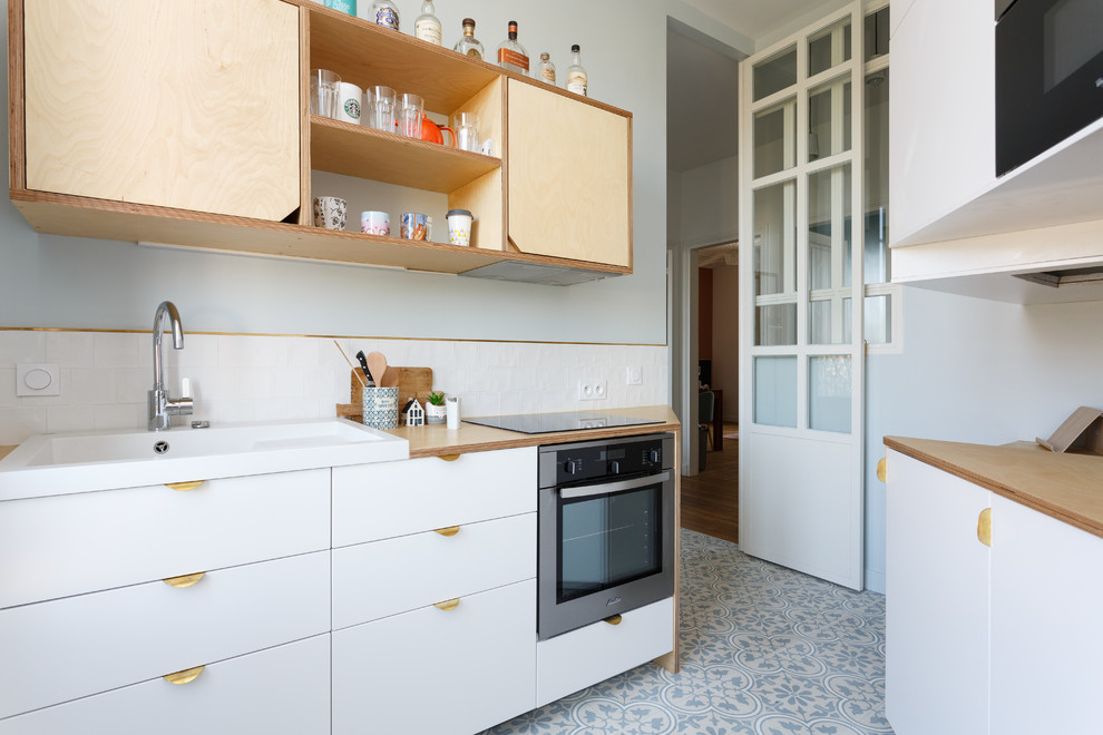 Inspiration for a mid-sized scandinavian galley cement tile floor and blue floor enclosed kitchen remodel in Paris with a single-bowl sink, flat-panel cabinets, white cabinets, wood countertops, white backsplash, ceramic backsplash, stainless steel appliances, no island and beige countertops