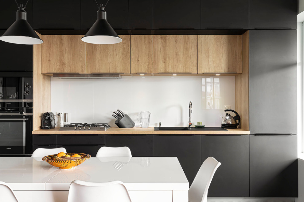 Inspiration for a large contemporary single-wall kitchen/diner in Lyon with a single-bowl sink, flat-panel cabinets, black cabinets, laminate countertops, white splashback, glass sheet splashback, integrated appliances, cement flooring, no island, black floors and beige worktops.