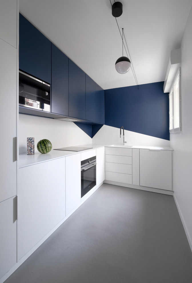 Idee per una cucina a L minimal con ante lisce, ante blu, elettrodomestici neri, pavimento in cemento, nessuna isola, pavimento grigio e top bianco