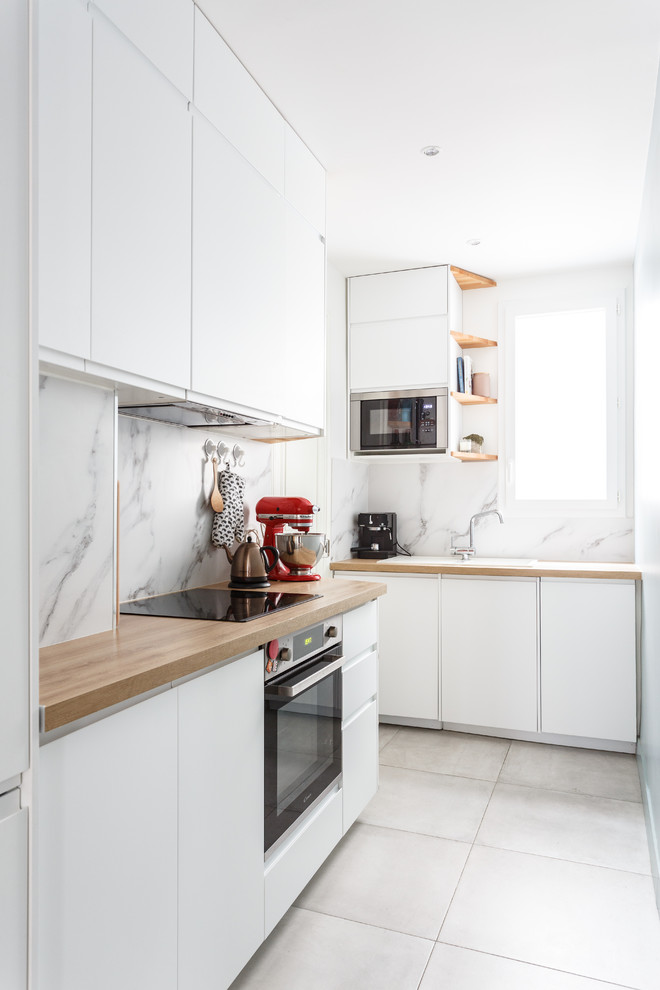 Exempel på ett avskilt, litet modernt beige beige l-kök, med en nedsänkt diskho, släta luckor, vita skåp, träbänkskiva, vitt stänkskydd, stänkskydd i marmor, rostfria vitvaror, klinkergolv i keramik och grått golv
