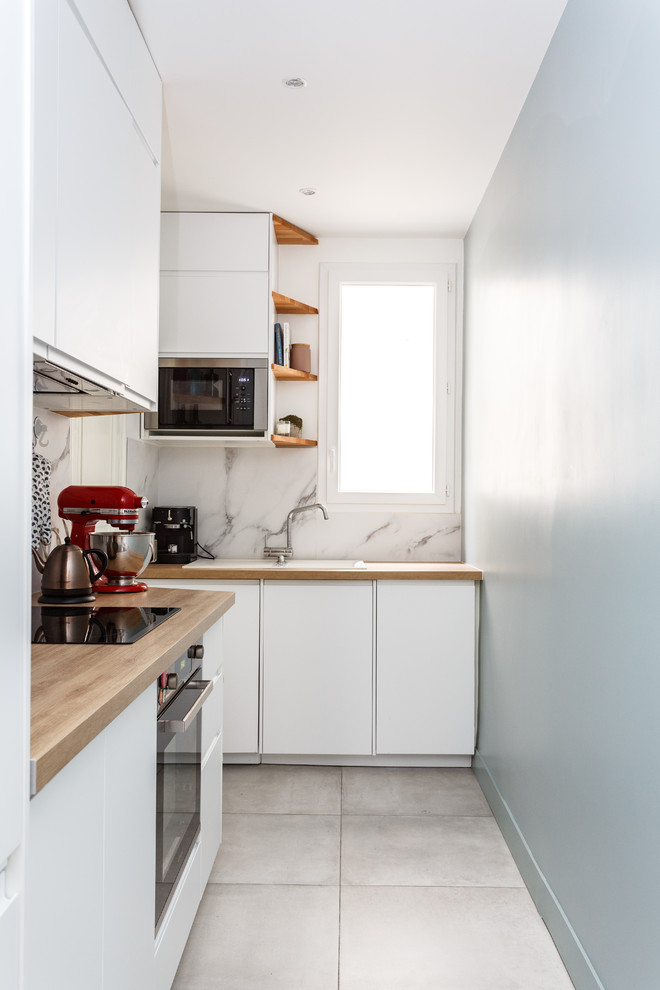 Small modern l-shaped enclosed kitchen in Paris with a built-in sink, flat-panel cabinets, white cabinets, wood worktops, white splashback, marble splashback, stainless steel appliances, ceramic flooring, no island, grey floors and beige worktops.